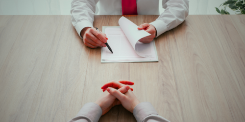 Hands of interviewer and interviewee with a folder between them.