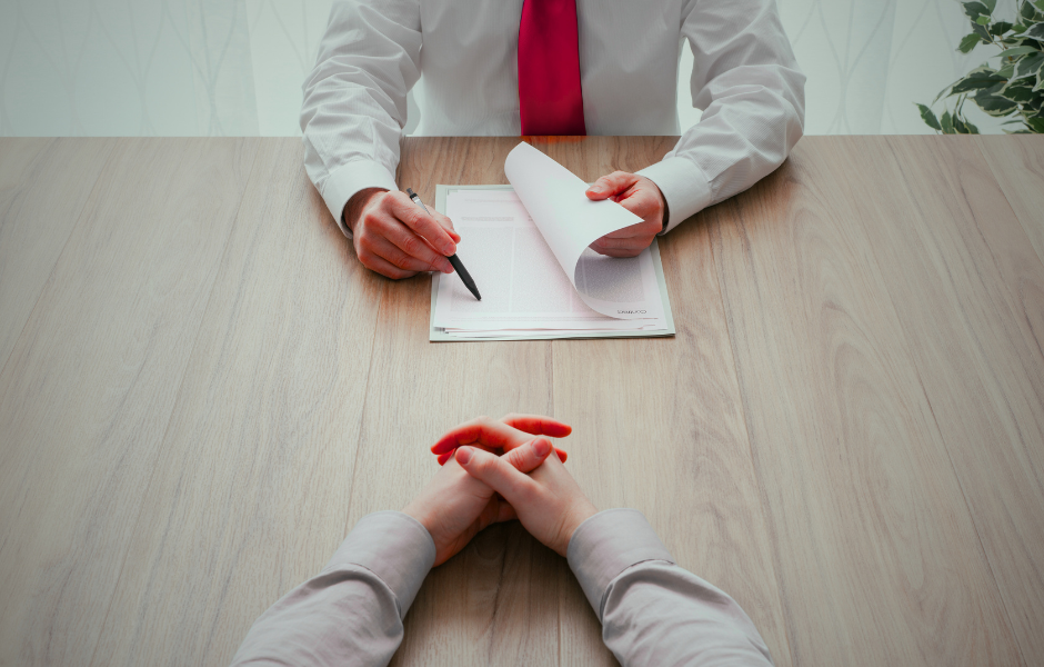 Hands of interviewer and interviewee with a folder between them.